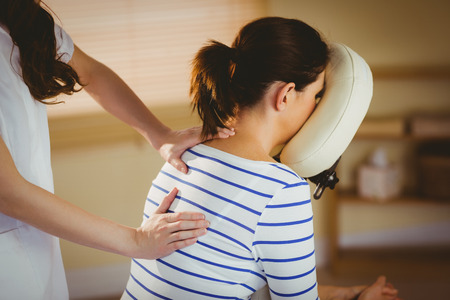 Young woman getting massage in chair in therapy roomの写真素材
