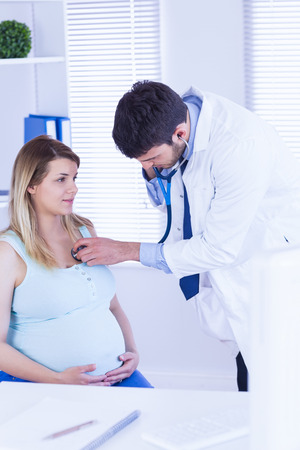 Doctor examining chest of pregnant patient in medical officeの写真素材