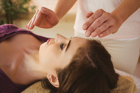 Young woman having a reiki treatment in therapy room