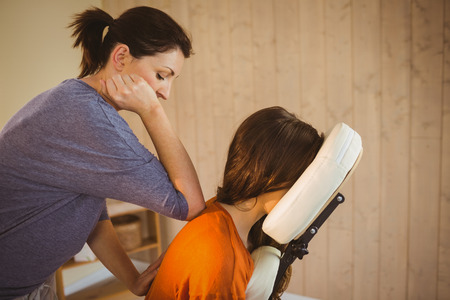 Young woman getting massage in chair in therapy roomの写真素材