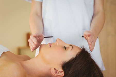 Young woman having a reiki treatment in therapy roomの写真素材