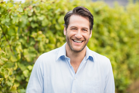 Young happy man smiling at camera in the grape fieldsの写真素材