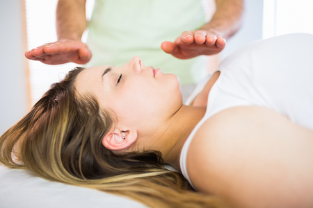 Close up view of relaxed pregnant woman getting reiki treatment in a studioの写真素材