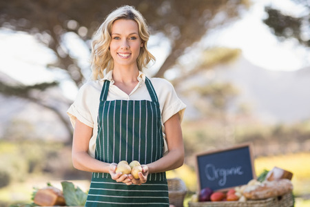 Portrait of a smiling farmer woman holding potatoesの写真素材