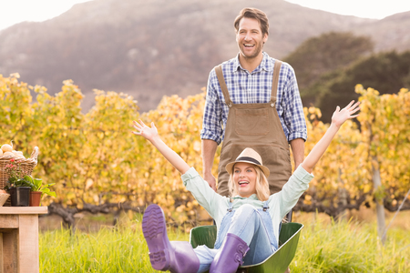 Couple in dungarees pushing a wheelbarrow in the countrysideの写真素材