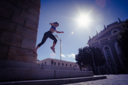 Athletic woman jumping off the stairs in the city