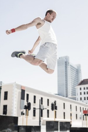 Man doing parkour in the city on a sunny dayの写真素材