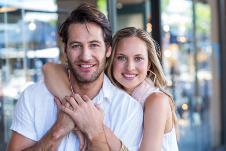 Portrait of smiling woman putting arm around her boyfriend at shopping mallの写真素材
