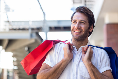 A happy smiling man with shopping bags in a clothing storeの写真素材