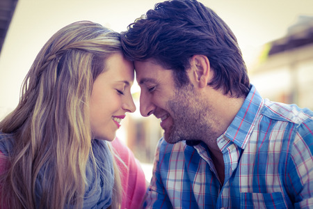 Cute couple sitting at a cafe head to head on a sunny dayの写真素材