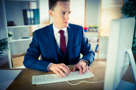 Stylish businessman working at his desk in his officeの写真素材