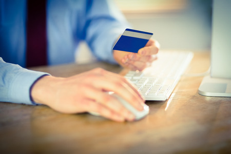 Businessman shopping online at desk in his officeの写真素材