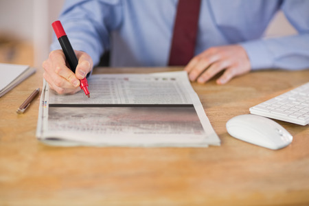 Businessman marking the newspaper with marker in his officeの写真素材