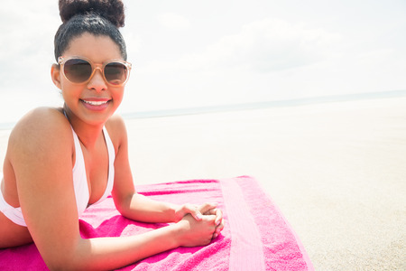 Smiling woman sunbathing on towel at the beachの写真素材
