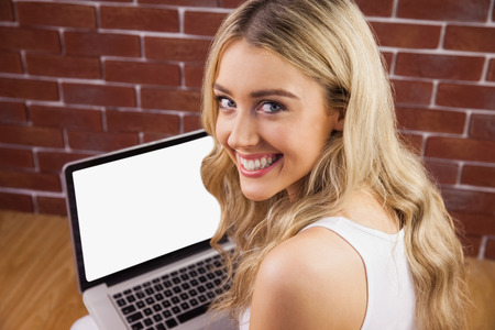 Portrait of a beautiful woman with laptop on her knee siting on the floorの写真素材