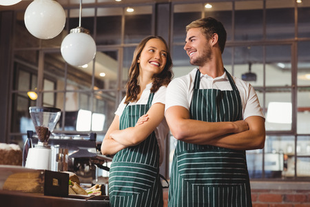 Co-workers standing together with arms crossed at the coffee shopの写真素材