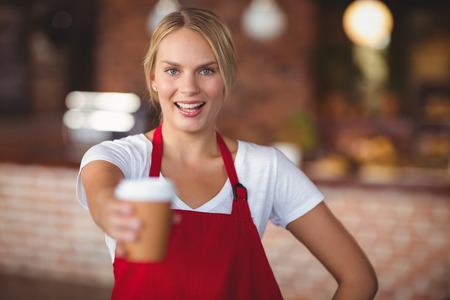 Portrait of a waitress handing a mug of coffee at the coffee shop