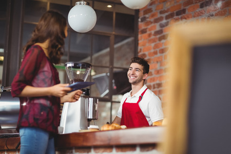 Handsome barista discussing with a customer at the coffee shopの写真素材