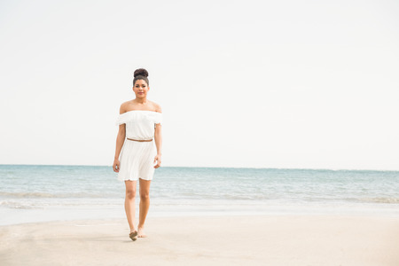Stylish woman walking on the sand at the beachの写真素材