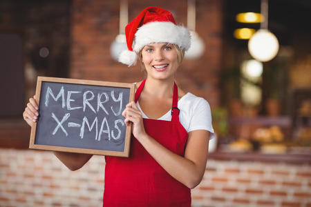 Portrait of a waitress with a chalkboard merry x-mas at the coffee shopの写真素材