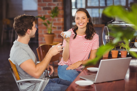 Portrait of smiling friends enjoying coffee together at coffee shopの写真素材