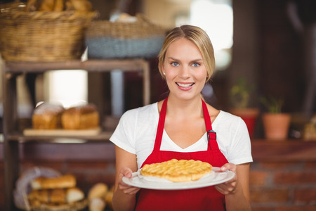 Portrait of a waitress holding a plate of cake at the coffee shopの写真素材
