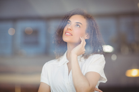 Thoughtful woman looking through the coffee shop windowsの写真素材