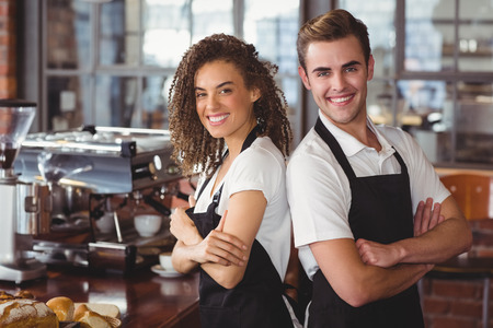 Portrait of smiling colleagues standing back to back at coffee shopの写真素材