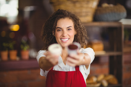 Portrait of a waitress showing two cupcakes at the coffee shopの写真素材
