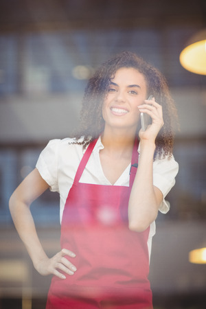 Portrait of a waitress talking on the phone at the coffee shopの写真素材