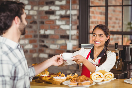 Smiling waitress serving a client at the coffee shopの写真素材