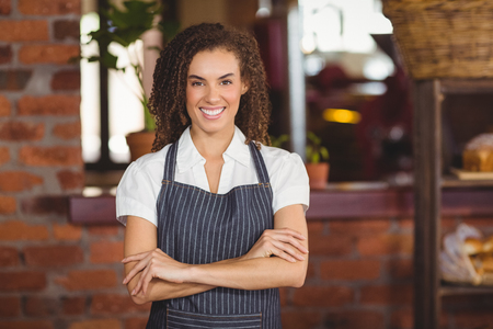 Portrait of smiling barista with arms crossed at coffee shopの写真素材