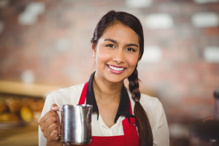 Portrait of a barista holding a milk jug at the coffee shopの写真素材