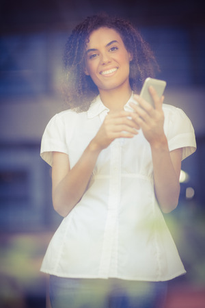 Portrait of a smiling woman sending a text at the coffee shopの写真素材
