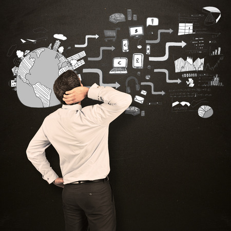 Thinking businessman scratching head against blackboardの写真素材