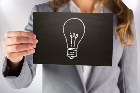 Businesswoman showing card against grey backgroundの写真素材