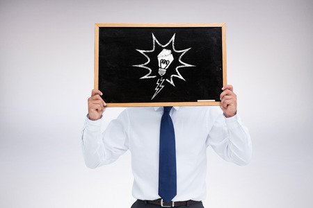 Businessman showing board against grey backgroundの写真素材