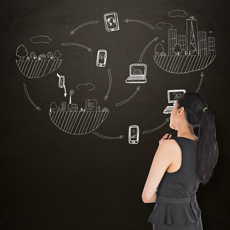 Thoughtful asian businesswoman against blackboardの写真素材
