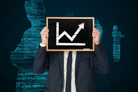 Businessman holding board against blue silhouettes on black backgroundの写真素材