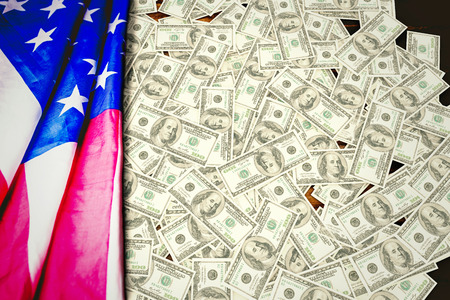 Pile of dollars against usa flag on tableの写真素材