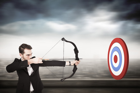 Elegant businessman shooting bow and arrow against cityscapeの写真素材