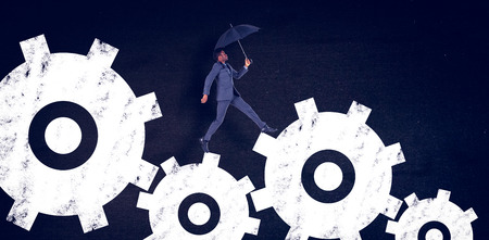 Businessman walking and holding umbrella against blackの写真素材