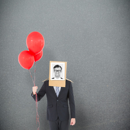Businessman with photo box on head against grey backgroundの写真素材