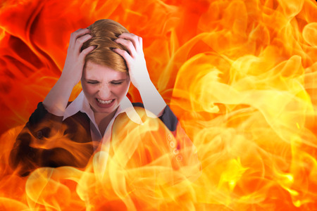 Stressed businesswoman with hands on her head against fireの写真素材