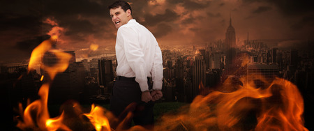 Rear view of young businessman wearing handcuffs against stormy sky over cityの写真素材