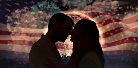 Attractive young couple about to kiss against colourful fireworks exploding on black backgroundの写真素材
