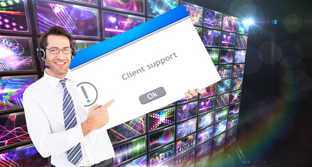 Businessman with headphone showing card to camera against client supportの写真素材