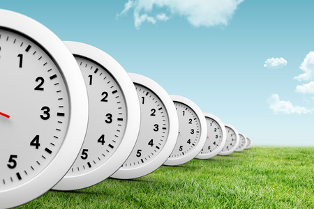 Clocks against blue sky over green field
