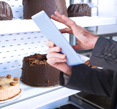 Businessman scrolling on his digital tablet against close up of desert like swiss roll and coffee cake