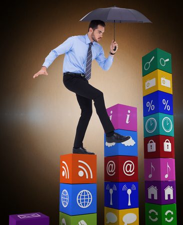 Focused businessman holding umbrella and balancing  against orange background with vignetteの写真素材
